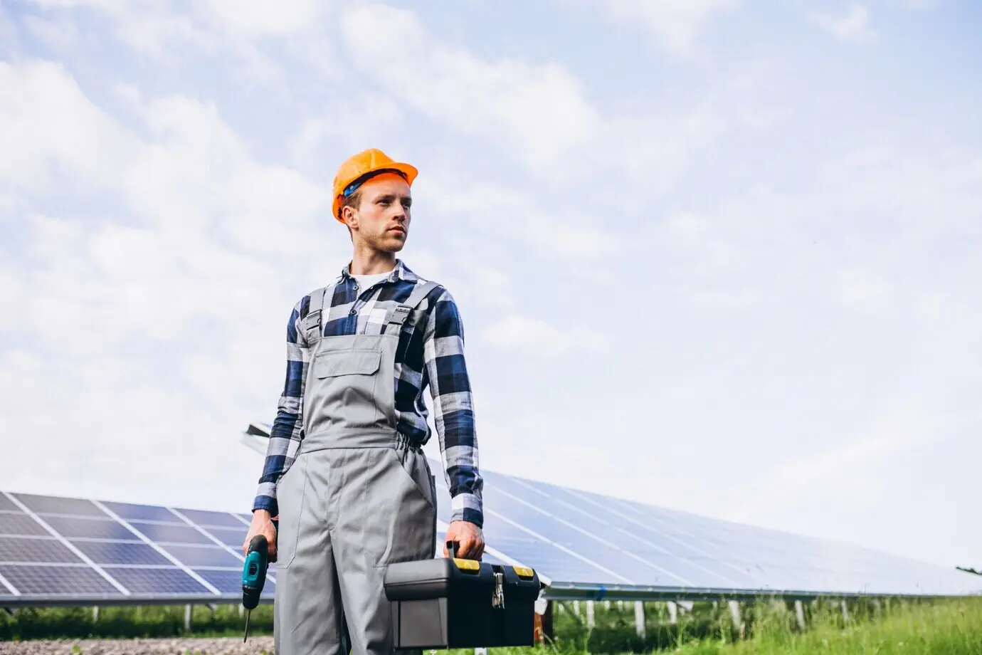 A man working in the field by the solar panels